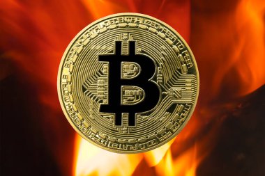 Fiziksel Bitcoin altın sikkesi (BTC) ateş ya da alev arkaplanlı. Artan fiyatlarla kripto para birimi boğa piyasası büyümesi.