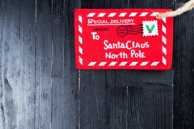 Noel Baba 'ya kırmızı mektup. Siyah doğal ahşap masaya sarılı jüt sicimi olan bir zarf. Noel çocuğu fantazisi soyut kavram.