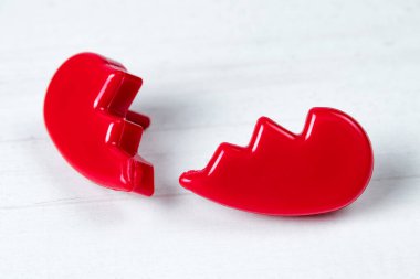 Kırık kırmızı sevgililer günü kalbinin iki yarısı beyaz ahşap arka planda. 