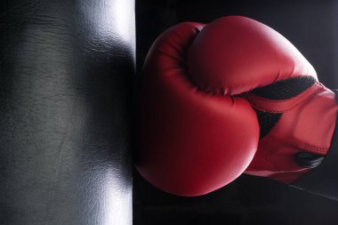 Sert adam boks eldiveniyle kum torbasına vuruyor. Kontrast aydınlatma görünümü.