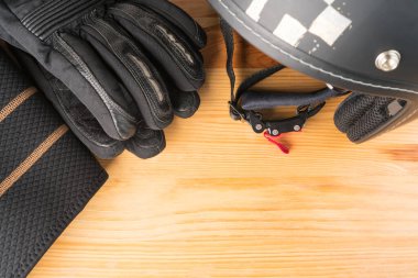 Motosiklet koruyucu teçhizat, kask, eldiven ve tahta arka planda böbrek kemeri. Düz manzaralı. Sağ alt köşeye boşluk kopyala.