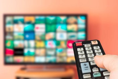 Beyaz bir adam evde ne izleyeceğini seçiyor. Talep üzerine video veya soyut VOD konsepti. Kanal değiştiriliyor ve sesi uzaktan kumandayla ayarlanıyor. 