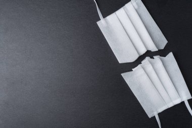 Koruyucu yüz maskesini koyu arkaplanda kes. Karantina ya da salgın soyut konseptin sonu. Uzayı sola kopyala.