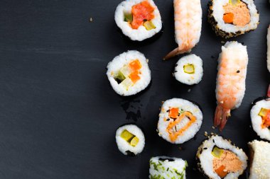 Siyah mutfak tabağında Japon suşisi. Tipik Asya mutfağı. Maki ve Nigiri. Uzayı sola kopyala.
