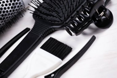 Siyah ve beyaz saç şekillendirme aletleri. Fırça, kurutma makinesi, beyaz doğal ahşap masa arkaplanının klipsi.