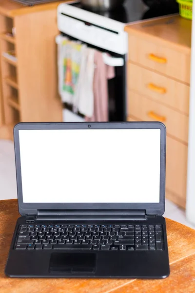 Laptop computer in vintage kitchen. Blank white screen ready for mockup. Old retro scratched wooden table.