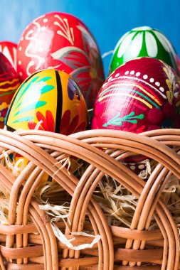 Renkli paskalya yumurtalarıyla hasır sepete yakın çekim. Dikey yönelim.