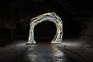 Noel ya da yeni yıl arifesi mavi ve sarı ışıklardan yapılmış bir parkın kapısı. Şenlikli dekorasyon.