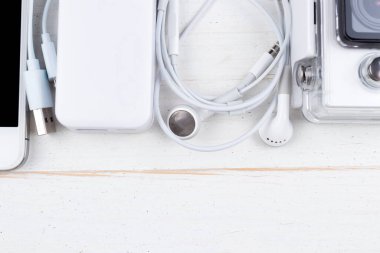 Beyaz teknoloji, doğal ahşap masa arka planında. Elektrik bankası, kablo, kulaklık, kamera, akıllı telefon. Alta uzayı kopyala. Düz üst görünüm.