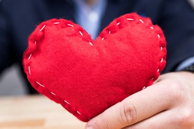 Sevgililer Günü 'nde kırmızı kalp tutan zarif genç bir adam. Mavi takım. 