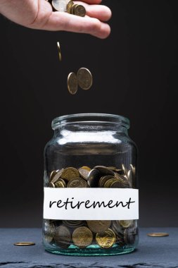 Kavanozdaki bozuk paralar ve beyaz etiketli emeklilik mesajları. Kafkasyalı adam yukarıdan para atıyor. Tasarruf kavramı. Uzayı kopyala Dikey yönelim.