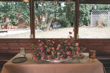 Ahşap bir kulübede pembe çiçeklerle düğün masası düzenlemesi