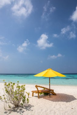 Bir güneşlenme ve ıssız bir sahilde plaj şemsiyesi; mükemmel bir tatil kavramı; mavi gökyüzü; şaşırtıcı deniz