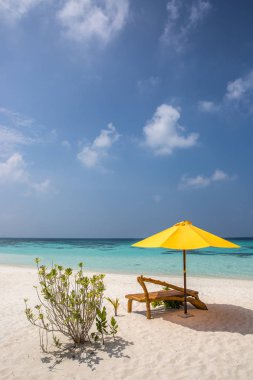 Bir güneşlenme ve ıssız bir sahilde plaj şemsiyesi; mükemmel bir tatil kavramı; mavi gökyüzü; şaşırtıcı deniz