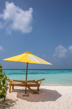 Bir güneşlenme ve ıssız bir sahilde plaj şemsiyesi; mükemmel bir tatil kavramı; mavi gökyüzü; şaşırtıcı deniz