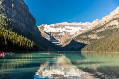 Muhteşem göl çevrili dağlar ve buzullar, turist kayık bir mavi gökyüzü günde Banff National Park Kanada'da yapıyor.