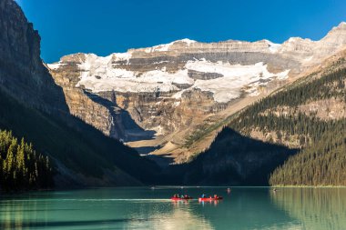 Muhteşem göl çevrili dağlar ve buzullar, turist kayık bir mavi gökyüzü günde Banff National Park Kanada'da yapıyor.