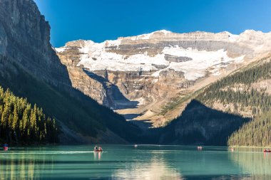 Muhteşem göl çevrili dağlar ve buzullar, turist kayık bir mavi gökyüzü günde Banff National Park Kanada'da yapıyor.