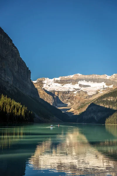 Muhteşem göl çevrili dağlar ve buzullar, turist kayık bir mavi gökyüzü günde Banff National Park Kanada'da yapıyor.