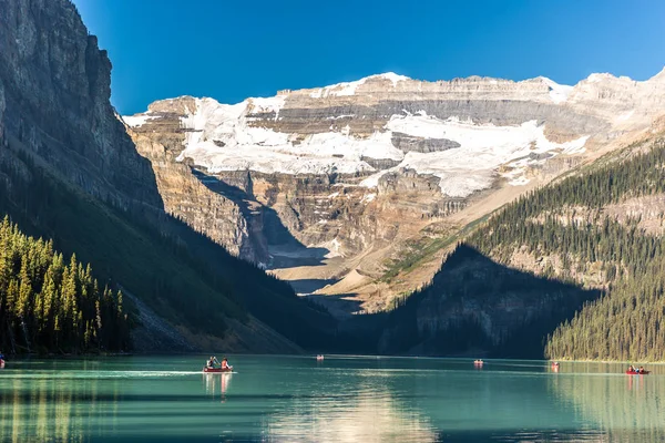 Muhteşem göl çevrili dağlar ve buzullar, turist kayık bir mavi gökyüzü günde Banff National Park Kanada'da yapıyor.
