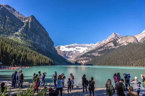 Banff, Kanada - önce 14 2017 - turist Gölü buzultaş önünde sabahın erken saatlerinde grup. Mavi gökyüzü, arka plan dağlarda, ağaçlarda Banff Kanada tonları.