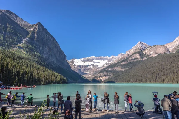 Banff, Kanada - önce 14 2017 - turist Gölü buzultaş önünde sabahın erken saatlerinde grup. Mavi gökyüzü, arka plan dağlarda, ağaçlarda Banff Kanada tonları.