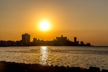 Havana, Küba'da arka planda binaları ile denizde turuncu günbatımı