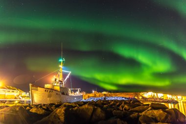 Amazing northern lights at Iceland, boat and rocks in the foreground. clipart
