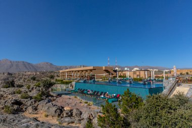 Al Jabal, Oman - Jan 22nd 2018 - The open swimming pool of the Anantara hotel in Al Jabal in Oman in a blue sky day. clipart