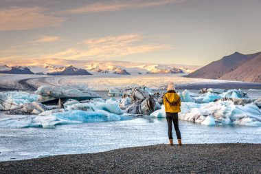 Genç kadın görmek şaşırtıcı Jokulsarlon, buzdağı lagün İzlanda'daki soğuk Giysi Giydirme
