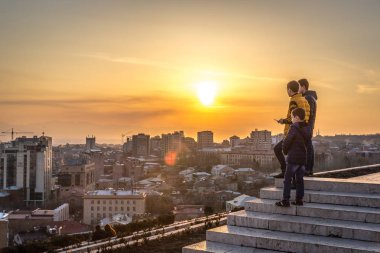 Yerevan, Armenia - Jan 8th 2018 - Locals enjoying the sunset at the top of the Cascade with Yerevan city in the background clipart