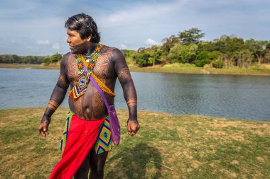 Embera Drua Villiage, Panama - Mar 3rd 2018 - An indigenous man dressing with his traditional clothes and paints in the edge of a river at Embera Drua Villiage in Panama clipart