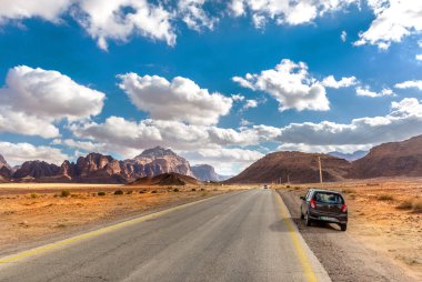 Wadi Rum, Ürdün - 17 Şubat 2018 - A Güney Jordan Wadi Rum çölde önünde boş bir yol arabaya mavi gökyüzü gün içinde kiraladı.