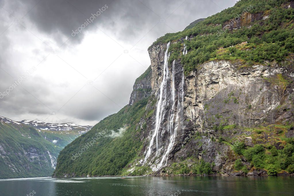 A waterfall in the middle of the fjords of Norway in a cloudy rainy day