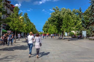 Priştine, Kosova - 30 Mayıs 2018 - büyük grup insan büyük yeşil ağaçlar ve Priştine, Kosova'nın başkenti mavi gökyüzü ile geniş bir kaldırım yürüyüş