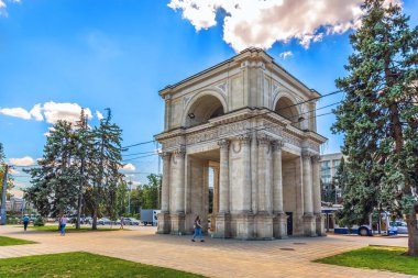 Chisinau, Moldavia - July 4th 2018 - Locals walking near by a huge arch in the downtown of Chisinau in Moldavia clipart