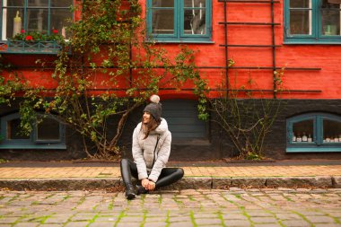 Mutlu bir gülümseme modern ve aydınlık bir sokakta oturup en iyi hayatı düşünüyor..