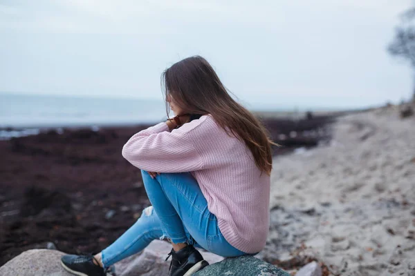 Üzgün ve bunalımlı genç bir kadın deniz kenarında tek başına oturmuş dizlerini kucaklıyor ve doğruca oturma odasına bakıyor. Depresyon öngörüsü. Kız tek başına oturur ve sorunlarını düşünür..