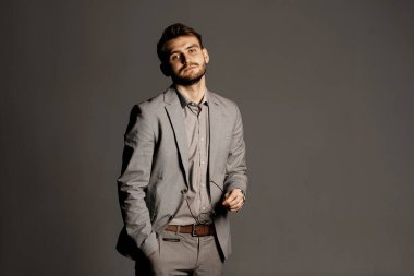 Kendinden emin ve ciddi bir adam bir şey düşünüyor ve kameraya bakıyor. Reklam metni için kopyalama uzayı. Genç öğretmen ve akıllı öğrenci. Stüdyo çekimi.