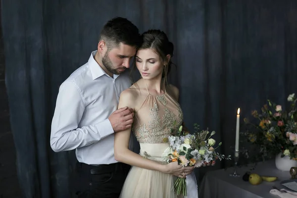 Güzel mutlu bir düğün çifti. Güzel geline nazikçe sarılan yakışıklı damat bakıyor. Portreyi kapat