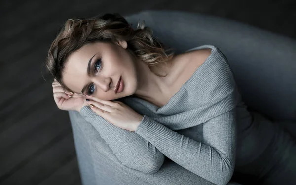 Gentle portrait of beautiful sensual young woman. Cute pretty woman with gentle make uo laying on the sofa and looking at camera. Closeup beauty portrait of calm youg woman.