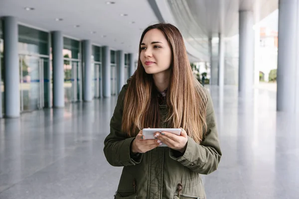 Una mujer joven y hermosa usa una tableta para comunicarse con sus amigos o mira un mapa o llama a un taxi u otra cosa. — Foto de Stock