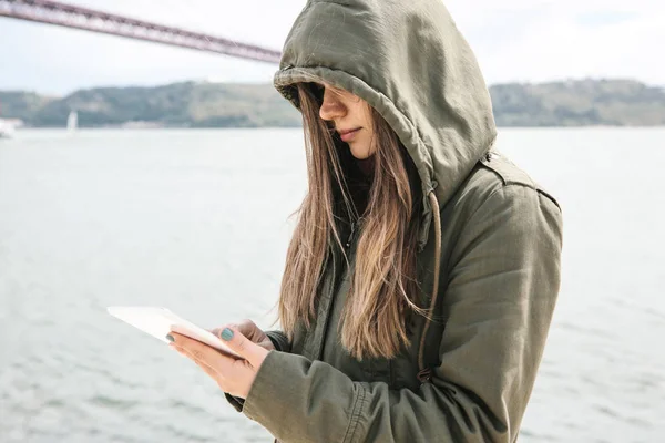 Una joven hermosa mujer utiliza una tableta para comunicarse con amigos o mira un mapa o algo más . — Foto de Stock