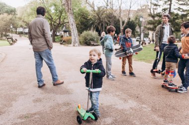 Lizbon, Portekiz 01 Mayıs 2018: bakım babalar çocukları ile yürümek ve kaykaylar ve scooter binmek için onlara öğretmek. Çocuklardan birinin ön planda öğrenmek bir scooter binmek için