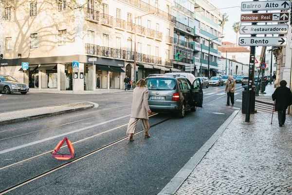 Lisbon, Portugal 01 may 2018: emergency or driver or woman puts road sign. Car costs on emergency signal or traffic on road. Expectation of tow truck or traffic police — Stock Photo, Image