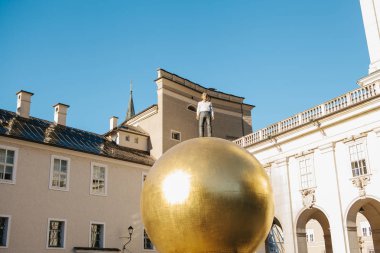 Avusturya, Salzburg - 01. 01. 2017. Altın top heykel adam resmi kıyafeti ile görünüm üstte güneş ışığı altında şehir meydanında yer