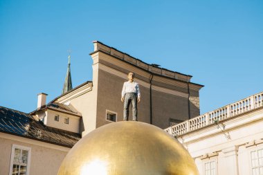 Avusturya, Salzburg - 01. 01. 2017. Altın top heykel adam resmi kıyafeti ile görünüm üstte güneş ışığı altında şehir meydanında yer