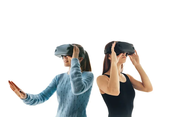 Дві молоді дівчата в окулярах віртуальної реальності на білому тлі. Концепція сучасних технологій і технологій майбутнього. VR окуляри — стокове фото