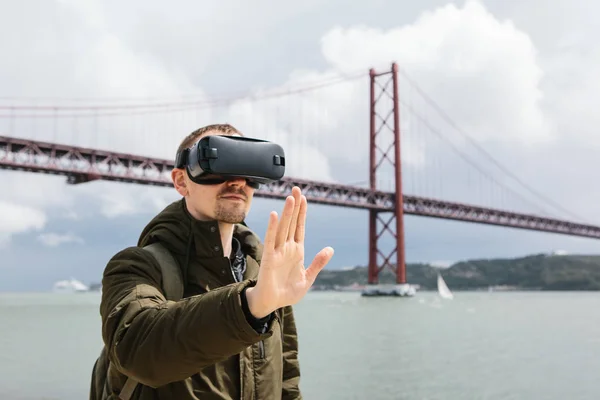 Людина використовує віртуальну реальність окуляри. 25 квітня мосту в Лісабоні у фоновому режимі. Концепція віртуальних подорожі. Концепція сучасні технології та їх застосування у повсякденному житті — стокове фото