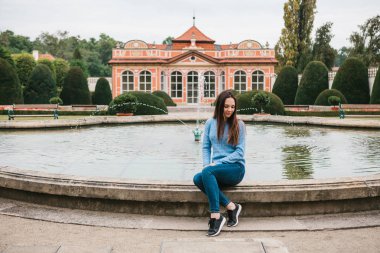 Güzel genç kız parkta bir çeşme yanında oturur ve bir dinlenme vardır